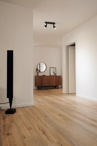 Décoration intérieure minimaliste avec parquet et bois Intérieur moderne épuré avec parquet en chêne, enceinte design noire, buffet en bois et miroir rond.